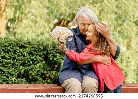 happy and laughing grandmother and her granddaughter in the park on a bench. Joyful meetings of family members Royalty-Free Stock Photo #2174268595