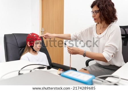 Doctor putting electrodes on a girl in a biofeedback session Royalty-Free Stock Photo #2174289685