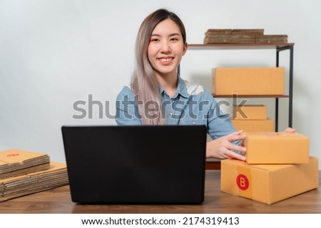 A young businesswoman is very happy after checking her email through her laptop.Online sellers are packing products into parcel boxes.