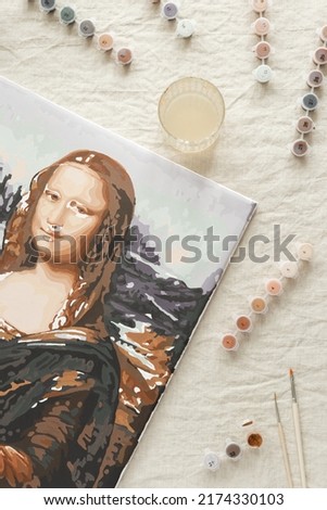 Painting by numbers with acrylic paints. Coloring Mona Lisa picture by numbers. Creative hobby for relaxation, leisure activity at home. Set to paint with canvas, paints, brushes. Top view