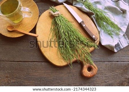 Fresh horsetail plant on a table with herbal tea on the wooden background . Royalty-Free Stock Photo #2174344323