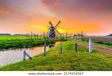 Mill by the river at sunset. Windmill farm at sunset. Beautiful sunset on windmill farm. Windmill at sunset landscape Royalty-Free Stock Photo #2174354367