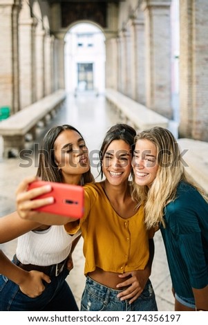Vertical shot of young happy group of multiracial best women friends taking selfie photo on cellphone outdoor during summer vacation in Italy - Travel and female friendship concept Royalty-Free Stock Photo #2174356197
