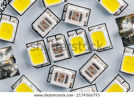Electronic light-emitting diodes on white circuit board inside household LED bulb. Close-up of yellow or clear semiconductor light sources of different color temperature. Electric lamp SMT components.