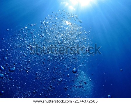 Bright exhale bubbles from scuba diver and sun in the blue ocean. Underwater scenery, sun light and bubbles of air rising.