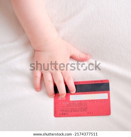 Baby toddler boy holds a credit card in his hand. Child with a bank plastic card, close-up