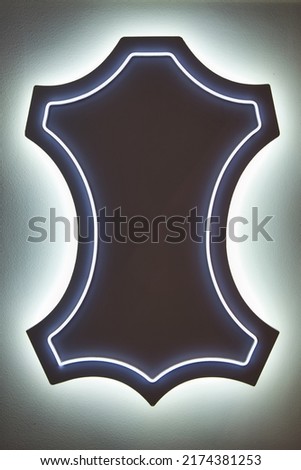 Neon-style sign showing the symbol of leather in front of a shoe store. Stylish abstract background for leather store or shoe store commercial. 