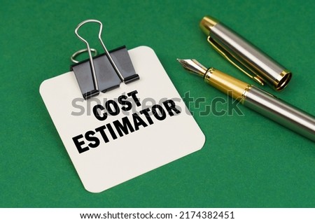 Business and industry concept. On a green surface, a pen and a sheet of paper with the inscription - Cost estimator