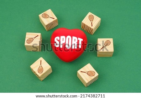 Sports concept. On a green surface, a heart with the inscription - sport and cubes with the image of a tennis racket