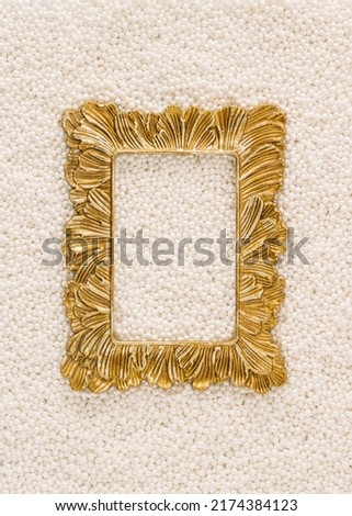 A creative arrangement made of a retro gold picture frame and white pearl beads. Minimal flat lay concept with copy space. Empty frame. Elegance inspiration.