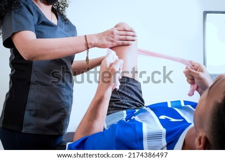 Knee Strengthening Physiotherapy, Neuromuscular Bandage Treatment. Physiotherapy exercises for knee strengthening, Knee Wrap Physiotherapy Royalty-Free Stock Photo #2174386497