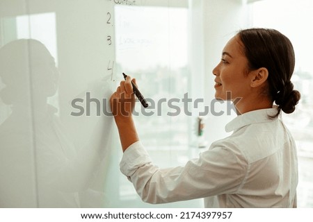 Smiling asian business woman write project plan on flipboard during meeting . High quality photo