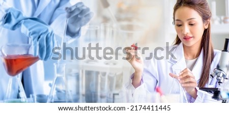 Attractive scientist woman testing chemical sample in flask at laboratory with lab glassware background. Science or chemistry research and