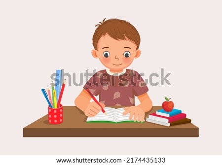 Cute little boy sitting on the desk studying writing on notebook doing her homework at home Royalty-Free Stock Photo #2174435133