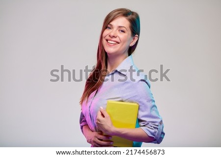 smiling woman teacher or happy student holding yellow book. adult student in grey shirt. isolated female portrait on gray background