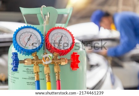 Manifold tool gauge bucket refrigerant applies to car air conditioning with blurred technician repairman check car air conditioning system refrigerant recharge, Air Conditioning Repair Royalty-Free Stock Photo #2174461239