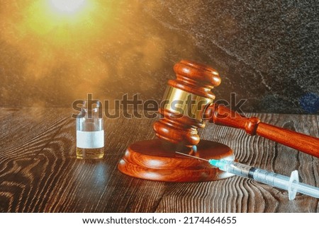 Judges hammer, syringe and vaccine bottle on a wooden background with sun light. Concept for a medical judgment