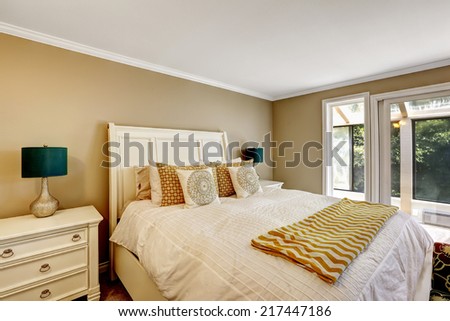 Bright bedroom with carved wood bed. Refreshing bedding with orange details