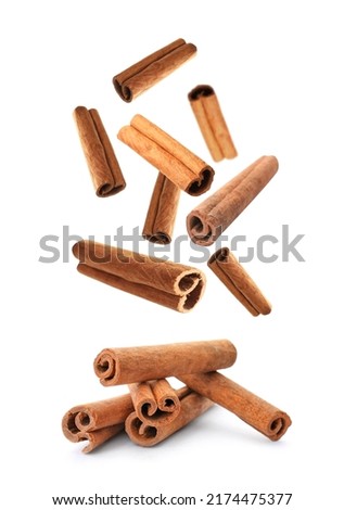 Aromatic cinnamon sticks falling on white background Royalty-Free Stock Photo #2174475377