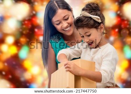 christmas, holidays, celebration, family and people concept - happy mother and child girl with gift box over red lights background
