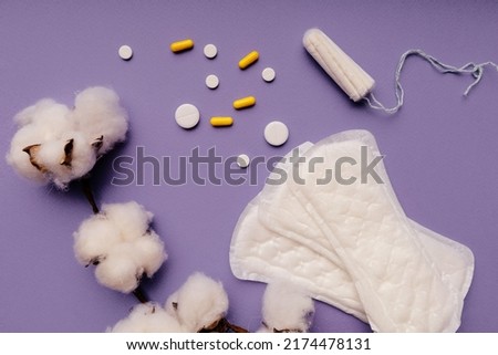 Woman hygiene protection, menstruation, sanitary pads and tampons with cotton on purple background.