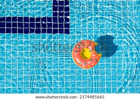 Donut float in swimming pool background with bright clear water at sunny day. Top view, copy space