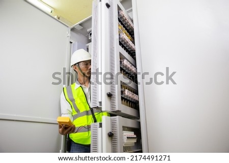 Electrician engineer work tester measuring voltage and current of power electric line in electical cabinet control.