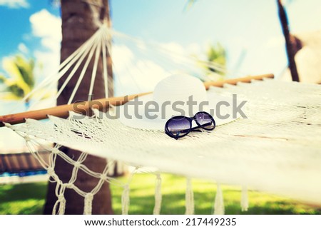 vacation and holiday concept - picture of hammock with white hat and sunglasses