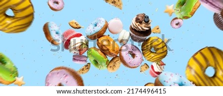 Confectionery as cakes, sweets, dougnuts collage on background. Colorful donuts, cookies, cupcakes, macaroons flying over blue background