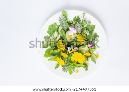 Top view of fresh dandelion salad with onion, cucumber and olive oil on a plate. Isolated on white background. Summer superfoods, raw food diet concept. Clean vegan eating.