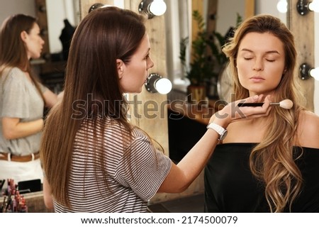 Pofessional make-up artist and her working process during makeup routine for young and beautiful model before photo shoot