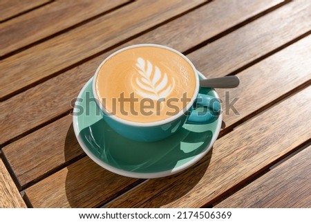 Cup of aromatic hot coffee and spoon on wooden table, above view