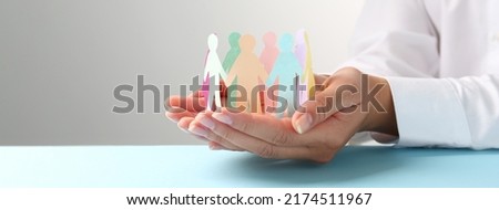 Woman holding paper human figures at table, closeup. Diversity and Inclusion concept Royalty-Free Stock Photo #2174511967