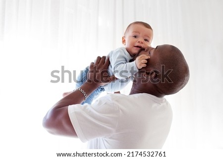 African American black dad kisses, holds on arms and loves baby son mixed race child against white background Royalty-Free Stock Photo #2174532761