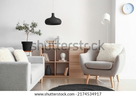 Comfortable grey furniture with wooden shelving unit and black lamp in light living room Royalty-Free Stock Photo #2174534917