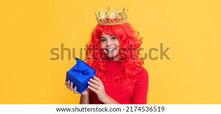 cheerful kid in crown with present box on yellow background