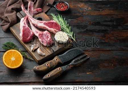 Fresh raw butchers lamb beef cutlets set, with ingredients carrot orange, herbs, on old dark  wooden table background , with copyspace  and space for text Royalty-Free Stock Photo #2174540593