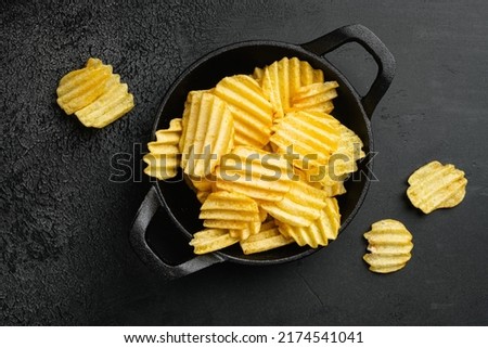 Wavy Ranch Flavored Potato Chips, on black dark stone table background, top view flat lay Royalty-Free Stock Photo #2174541041