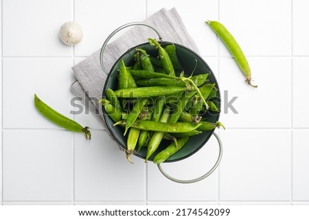 Green pea pod, on white ceramic squared tile table background, top view flat lay
