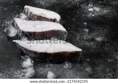 Halibut fish frozen steak set, on black dark stone table background