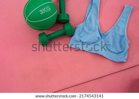 green round ball colored dumbbells barbell water female top spread out on a mat. Sports equipment concept