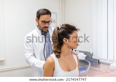 Shot of a doctor examining a young woman with a stethoscope, Lets have a listen to your lungs