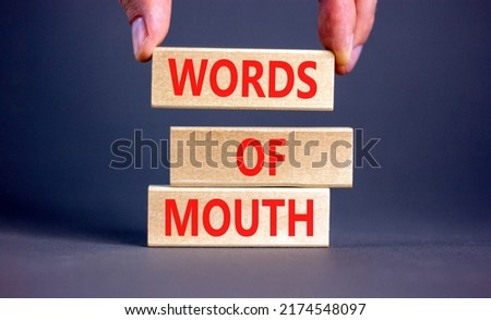 Words of mouth symbol. Concept words Words of mouth on wooden blocks on a beautiful grey table grey background. Businessman hand. Business, finacial and words of mouth concept. Copy space.
