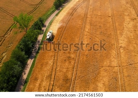 Aerial view of a combine harvester at work during harvest time. Cereal, grain shortage, high trading prices, stockpiling. Agricultural background.
