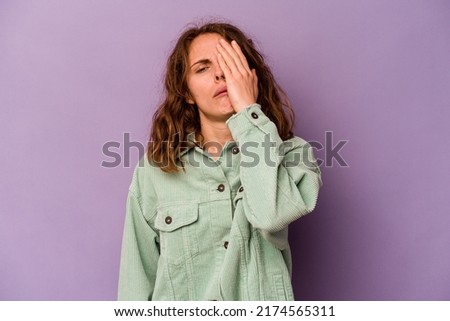 Young caucasian woman isolated on purple background tired and very sleepy keeping hand on head.