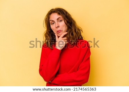 Young caucasian woman isolated on yellow background thinking and looking up, being reflective, contemplating, having a fantasy.