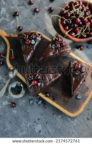 Dark chocolate cake with chocolate icing and seasonal cherries. Baking with alkalized cocoa with summer fruits and berries.