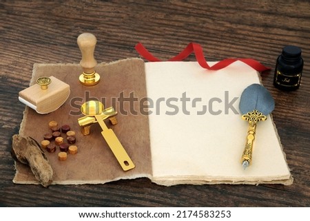 Old fashioned retro writing equipment with hemp notebook, quill feather pen, ink bottle, wax, spoon with rest, seal and blotter on rustic wood background. Copy space.