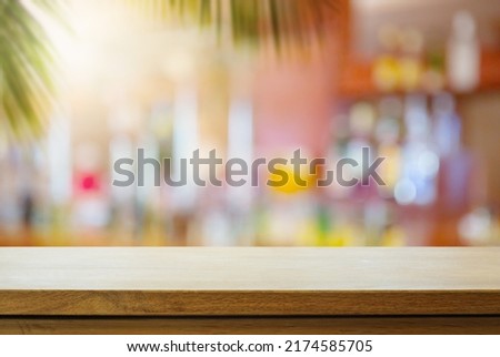 Empty wooden table on sunny blurred tropical bar background. Outdoor party mockup for design and product display.