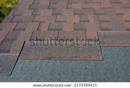 Laying asphalt shingles with vapor barrier on the house roof. Asphalt shingles installation on the rooftop.  Close up on Asphalt shingles texture background. Royalty-Free Stock Photo #2174589415